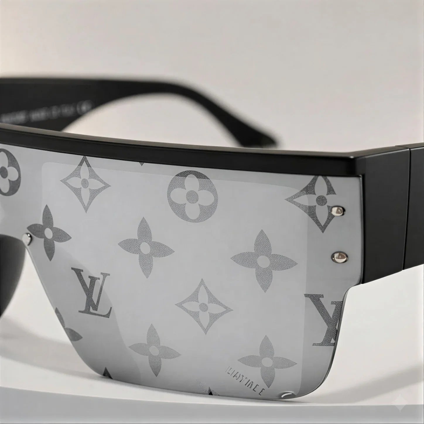 Close-up shot of Jazzo luxury sunglasses featuring silver monogram pattern lenses with black matte frame and silver stud detailing